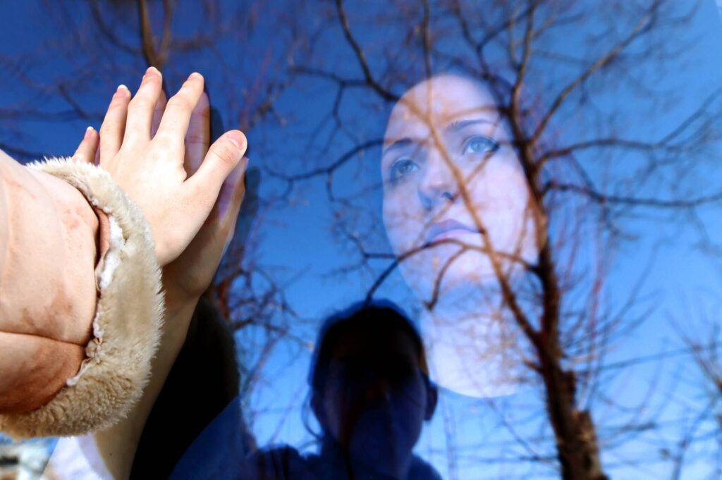 Femme songeuse à la fenêtre avec main et visage